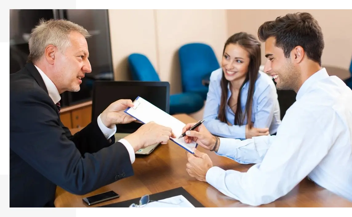 A man handing over papers to two people.